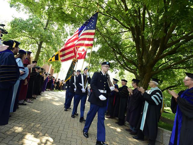 在毕业典礼上扛着国旗穿过校园.
